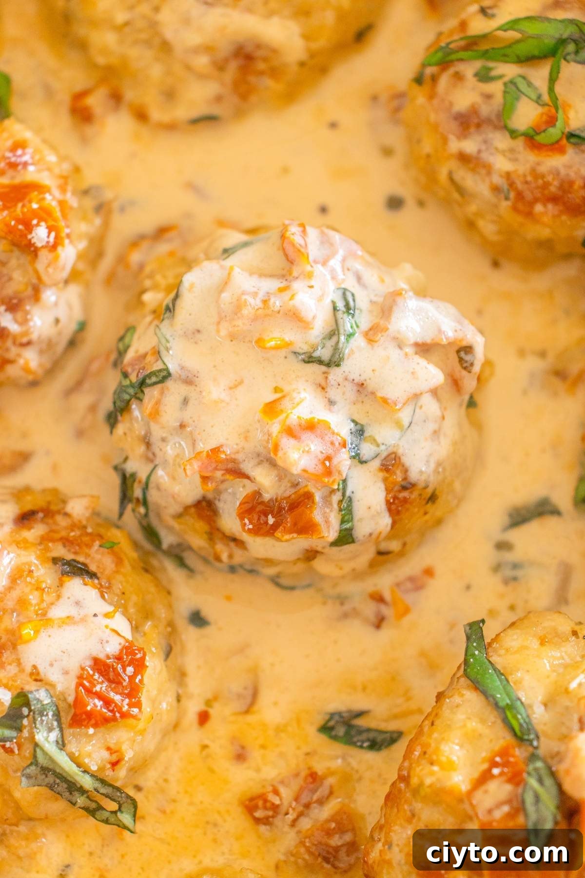 Marry me chicken meatballs simmered in a creamy sauce with diced tomatoes and basil.