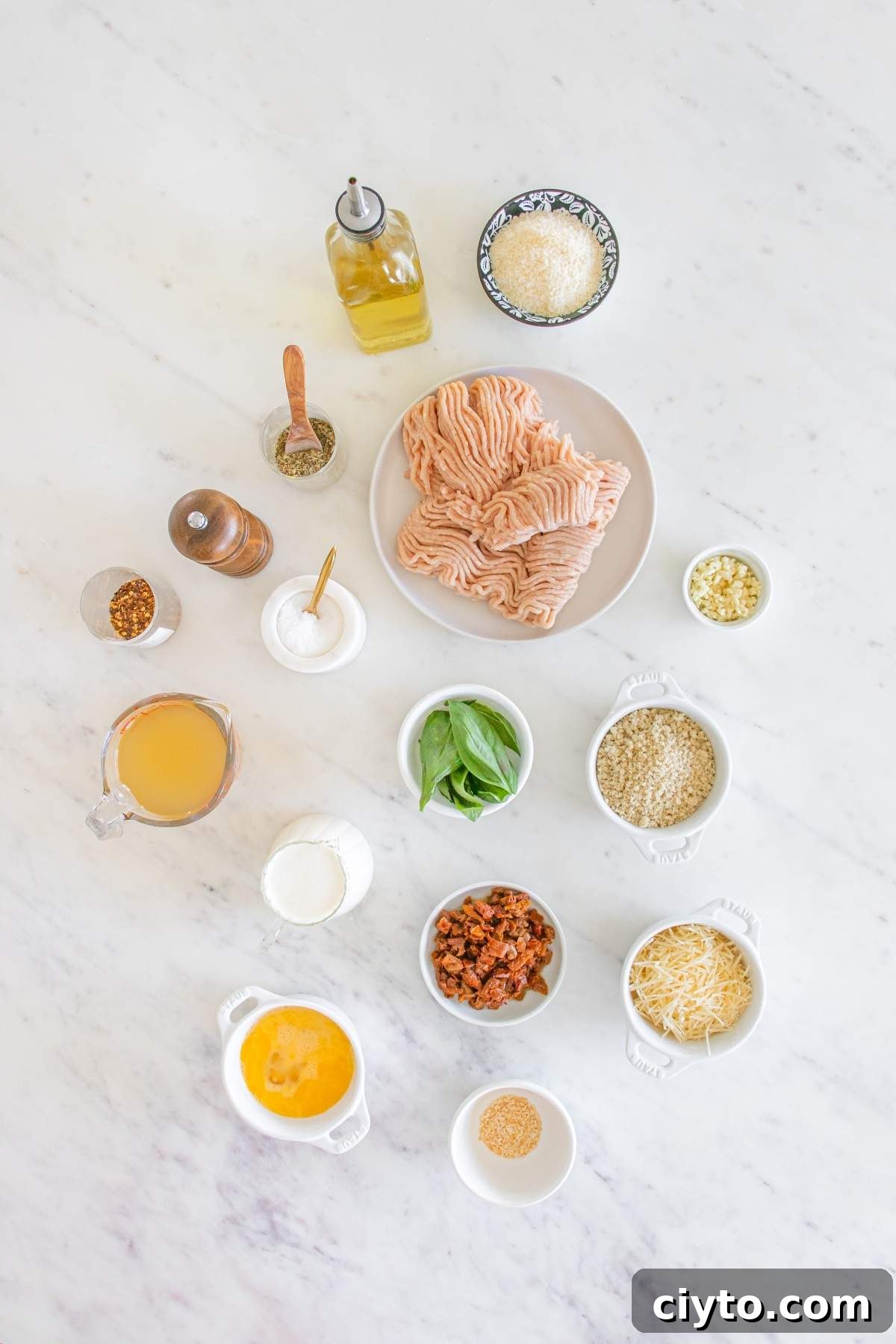 A countertop brimming with ingredients: raw ground meat ready to transform into delicious marry me chicken meatballs, accompanied by olive oil, cheese, seasonings, and fresh herbs, eagerly awaiting the culinary magic.