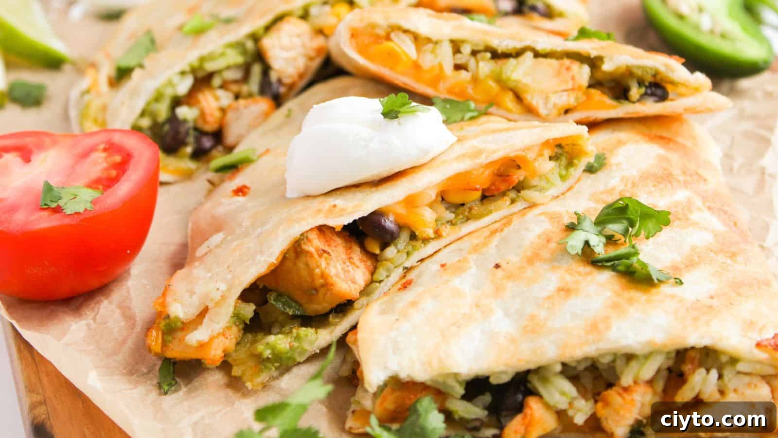 Quesadillas filled with rice, beans, and chicken, topped with sour cream and cilantro. Sliced tomato and jalapeño are on the side.