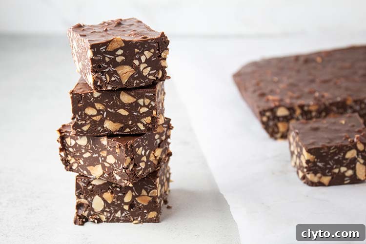 Low-Carb Peanut Butter Crunch Bars, Gluten Free, No Added Sugar 5 sideview of four homemade crunch bars stacked on a white surface with remaining crunchy bars to the right on white parchment paper