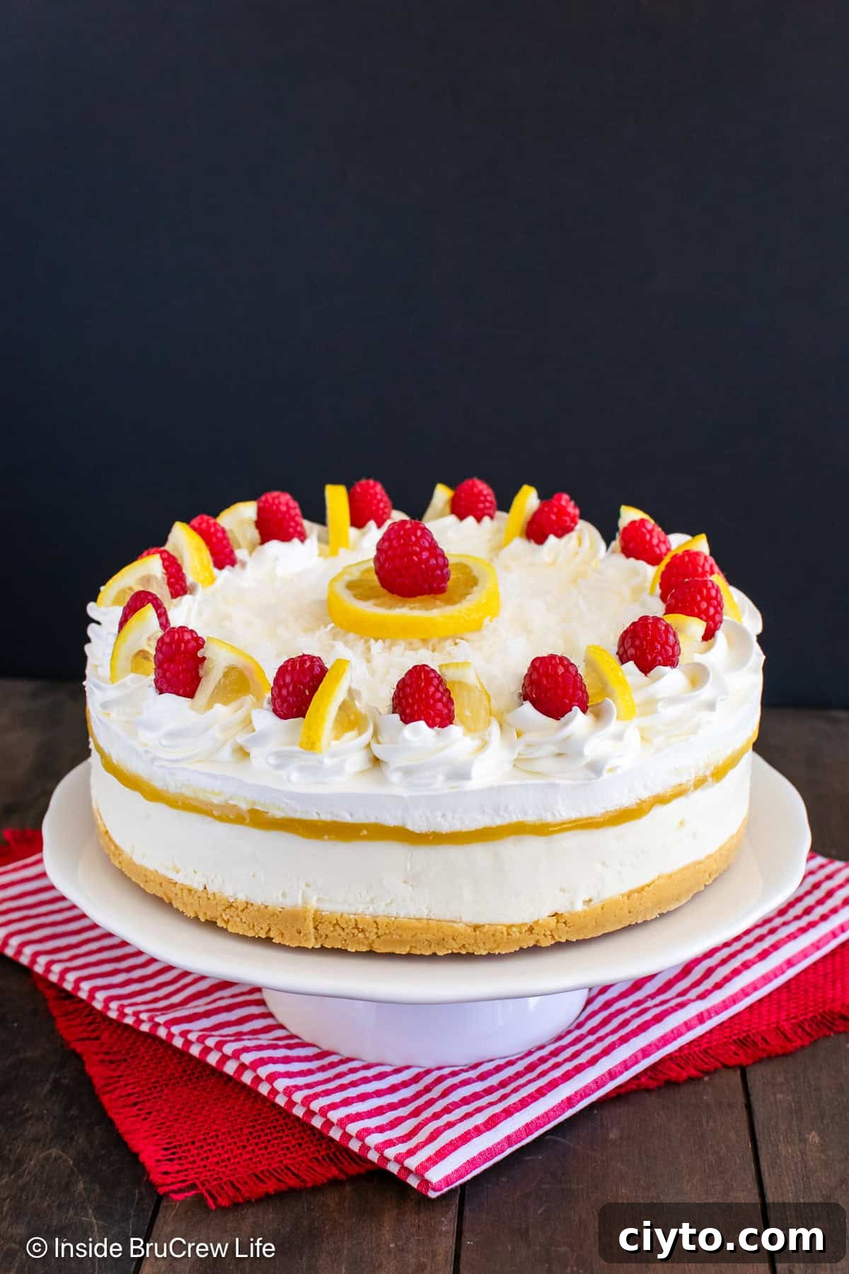 No-Bake Lemon Coconut Cheesecake Recipe 3 A full sized lemon coconut cheesecake on a white cake plate.