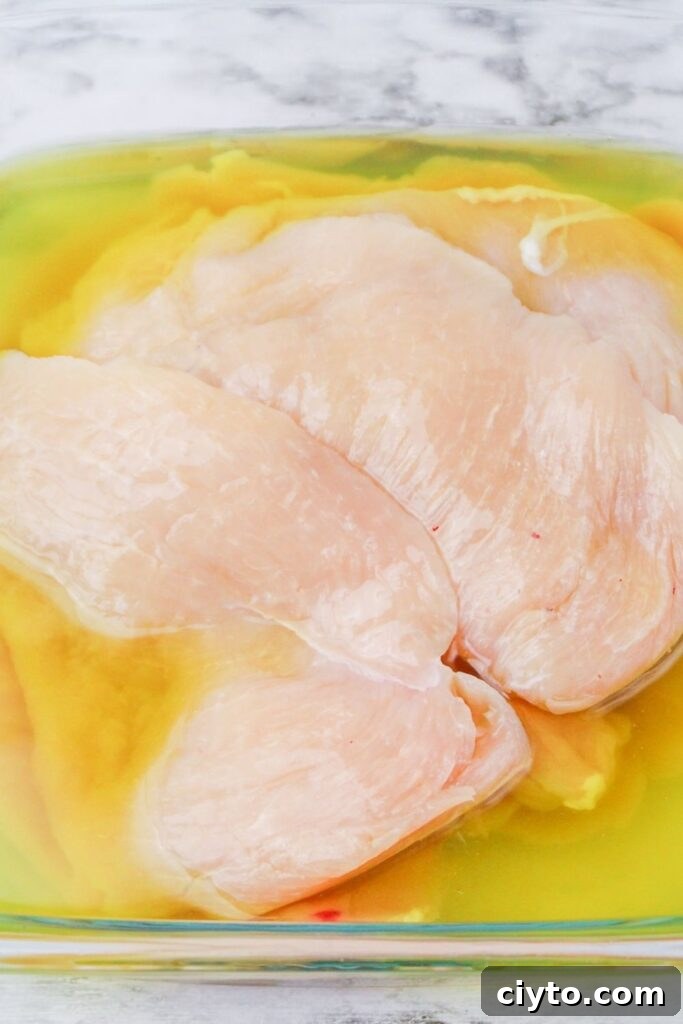 chicken soaking in pickle juice in glass container 