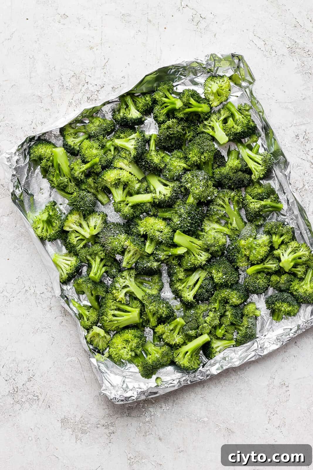 Broccoli florets in an aluminum foil boat after being coated in olive oil and salt sprinkled on top.