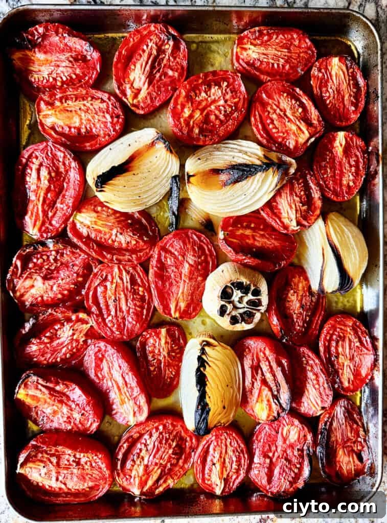 Roasted tomatoes, onions and garlic on a baking sheet