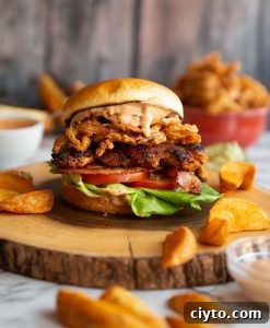 Chicken Sandwich chicken sandwich on wooden board surrounded by potato wedges and dip