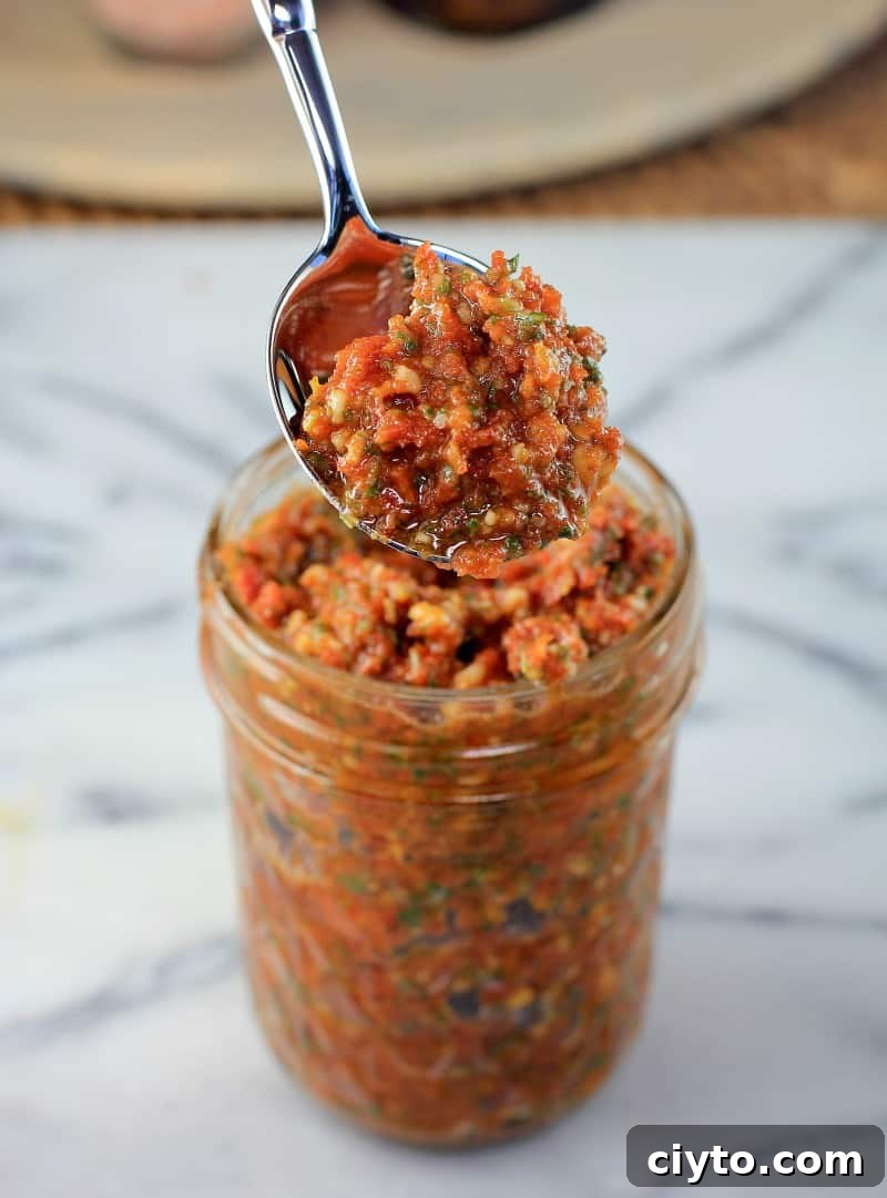 spoon lifting sun dried tomato pesto from a mason jar