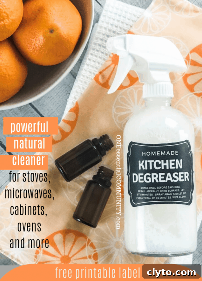 homemade kitchen degreaser spary with 2 essential oil bottles beside a bowl of oranges