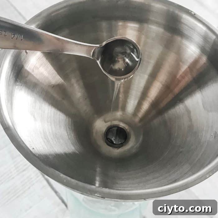 measuring spoon adding Castile soap to funnel