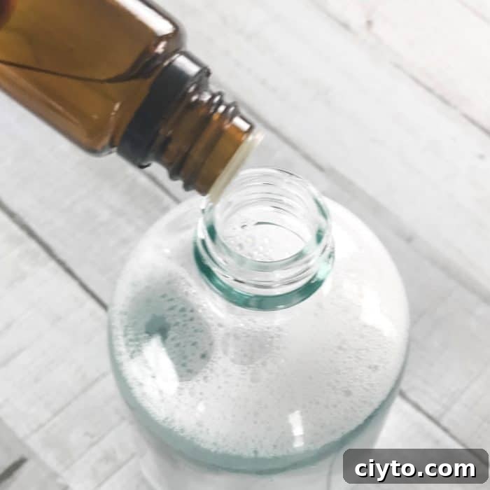 adding lemon essential oil and sweet orange essential oil to kitchen degreaser spray bottle