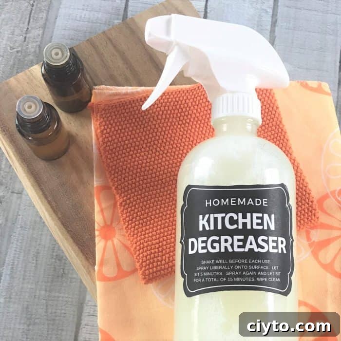 citrus kitchen cleaner on orange towels and wooden board next to essential oil bottles