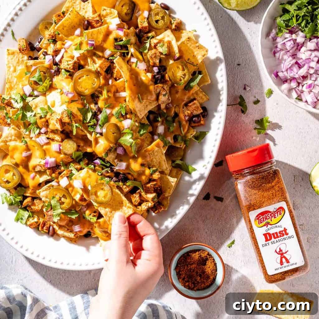 hand taking nacho from platter