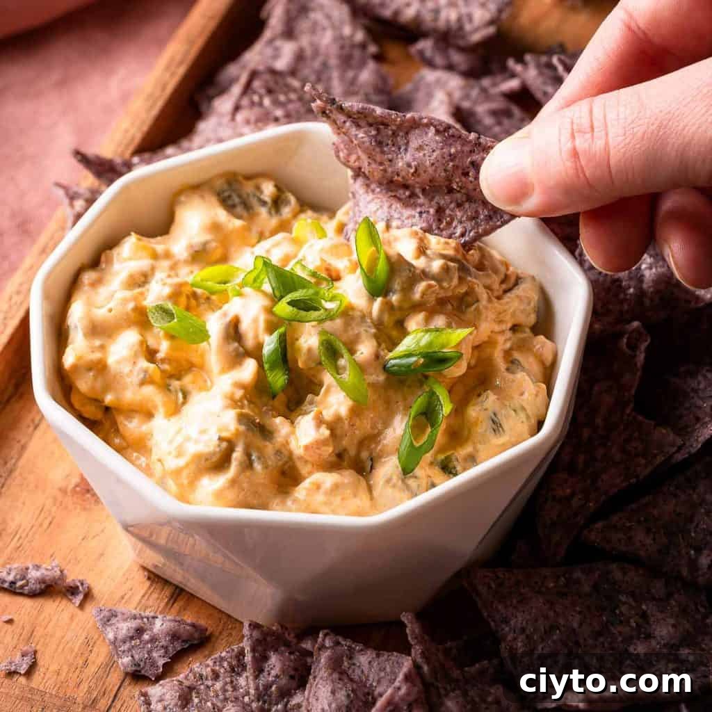 bowl of sausage cream cheese dip with chip being dipped