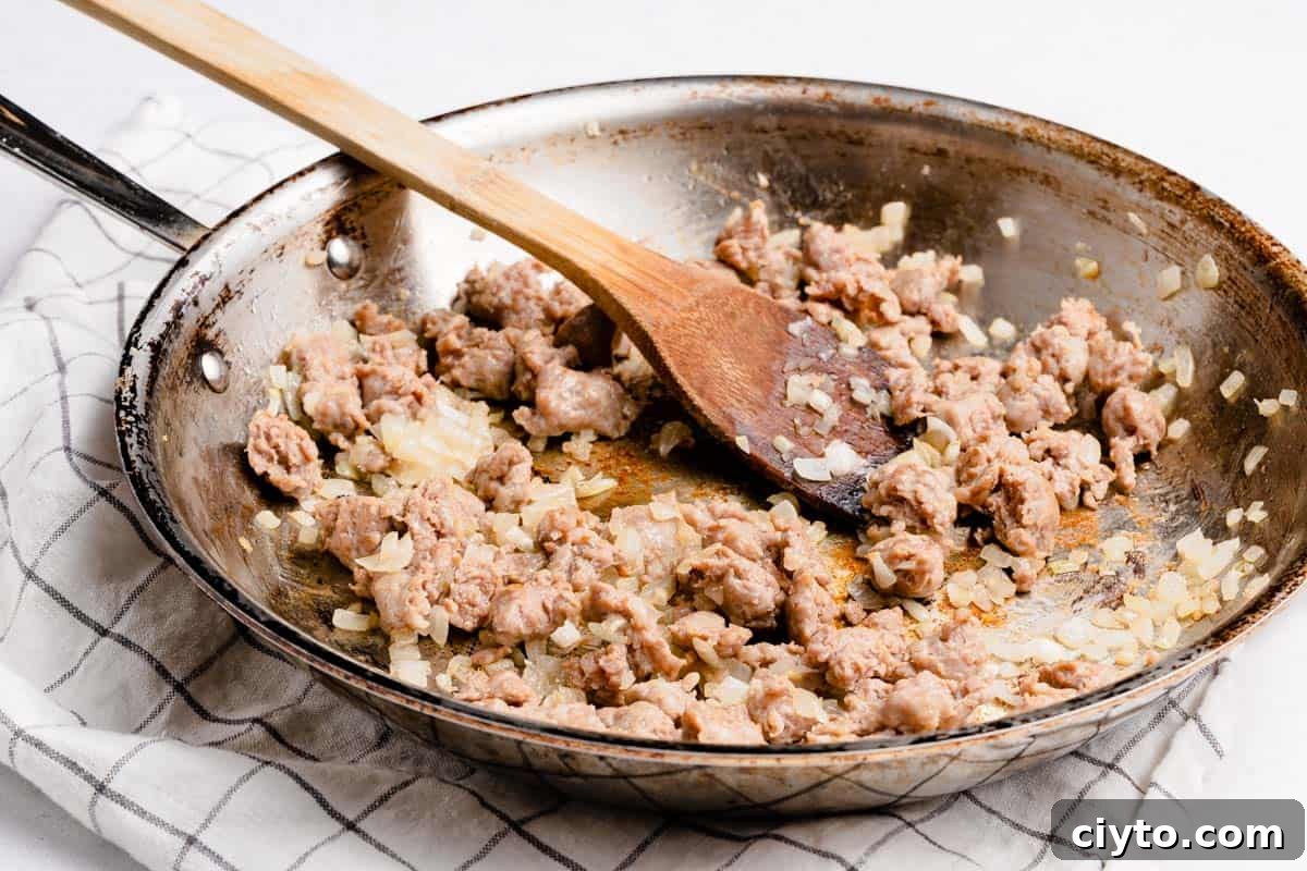 skillet with cooked crumbled sausage and chopped onion