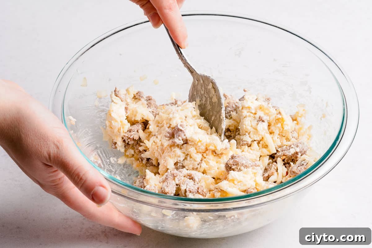 sausage and cheese filling being mixed in glass bowl with spoon