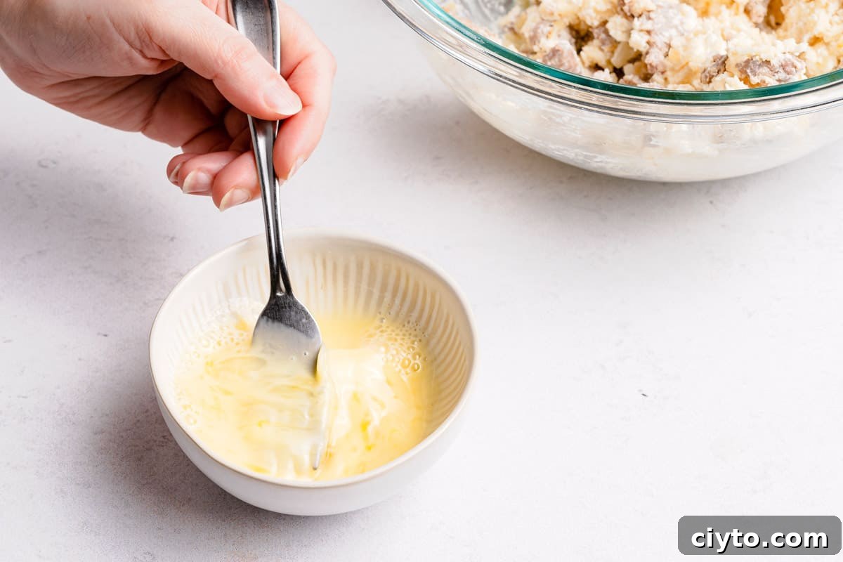 egg wash in small bowl being whisked with a fork