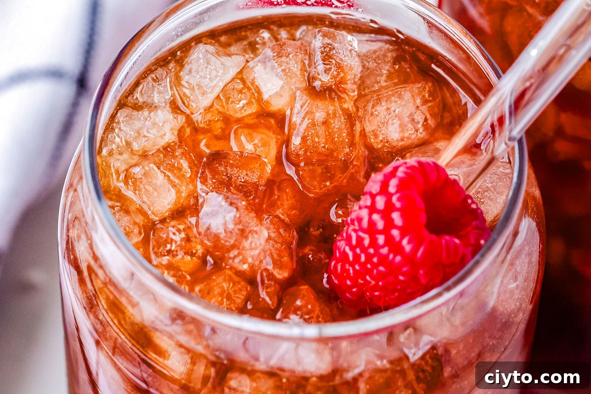 A Swig Raspberry Dream in a glass with pebble ice, a raspberry, and a straw.