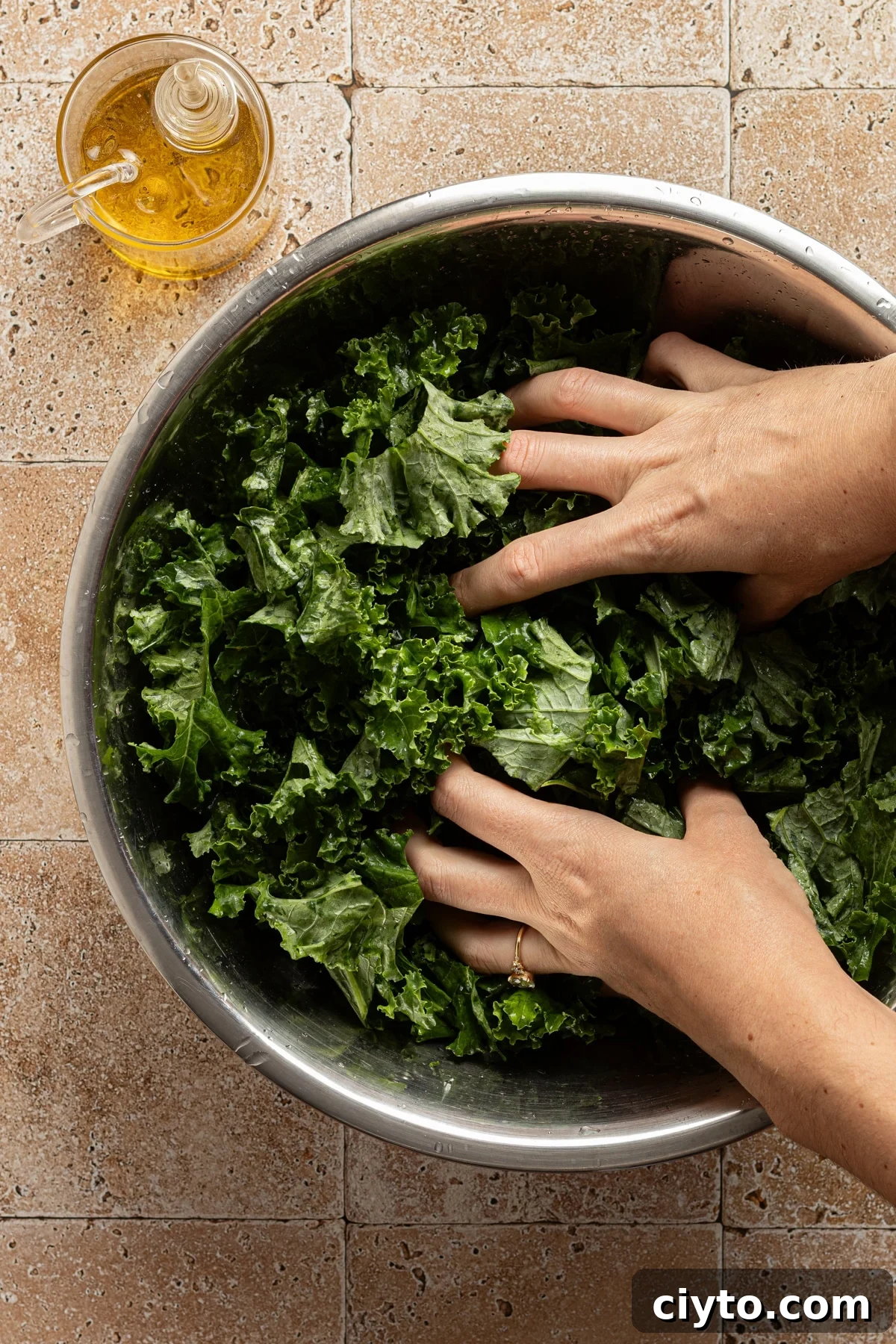 Kale and Butternut Squash Salad with Pomegranate and Apple 5 A bowl of kale being massaged with olive oil.