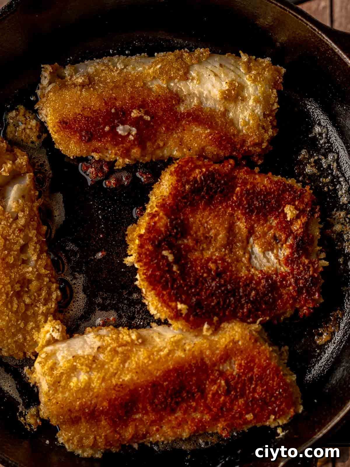 Breaded fish in a cast iron skillet.