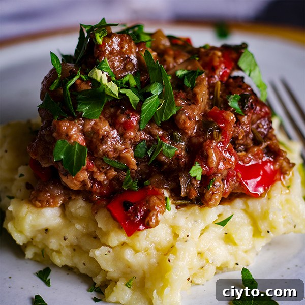 Slow-Braised Tuscan Beef with Garlic Mascarpone Mashed Potatoes 11 A plate of garlic mascarpone mashed potatoes topped with Tuscan Braised Beef and fresh parsley.