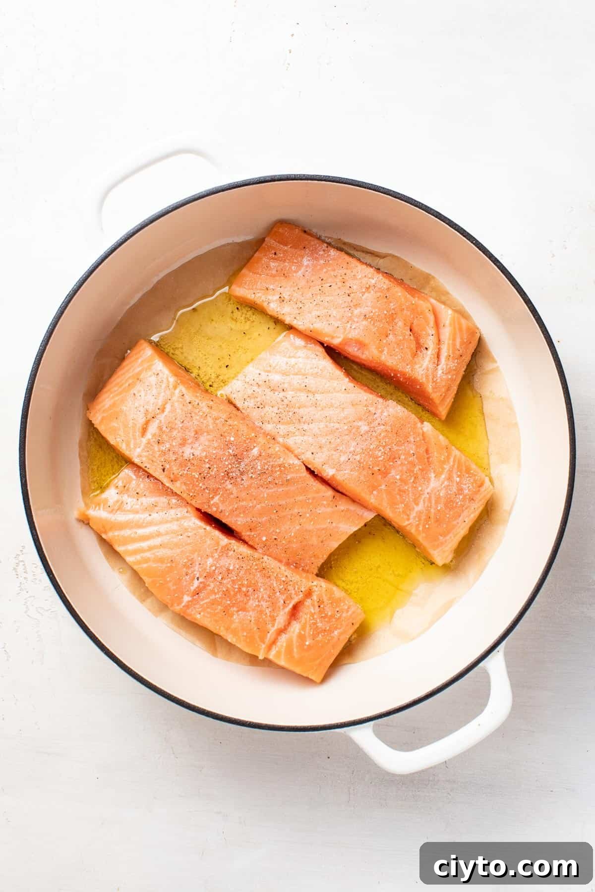 Four salmon fillets being seared in a pan.