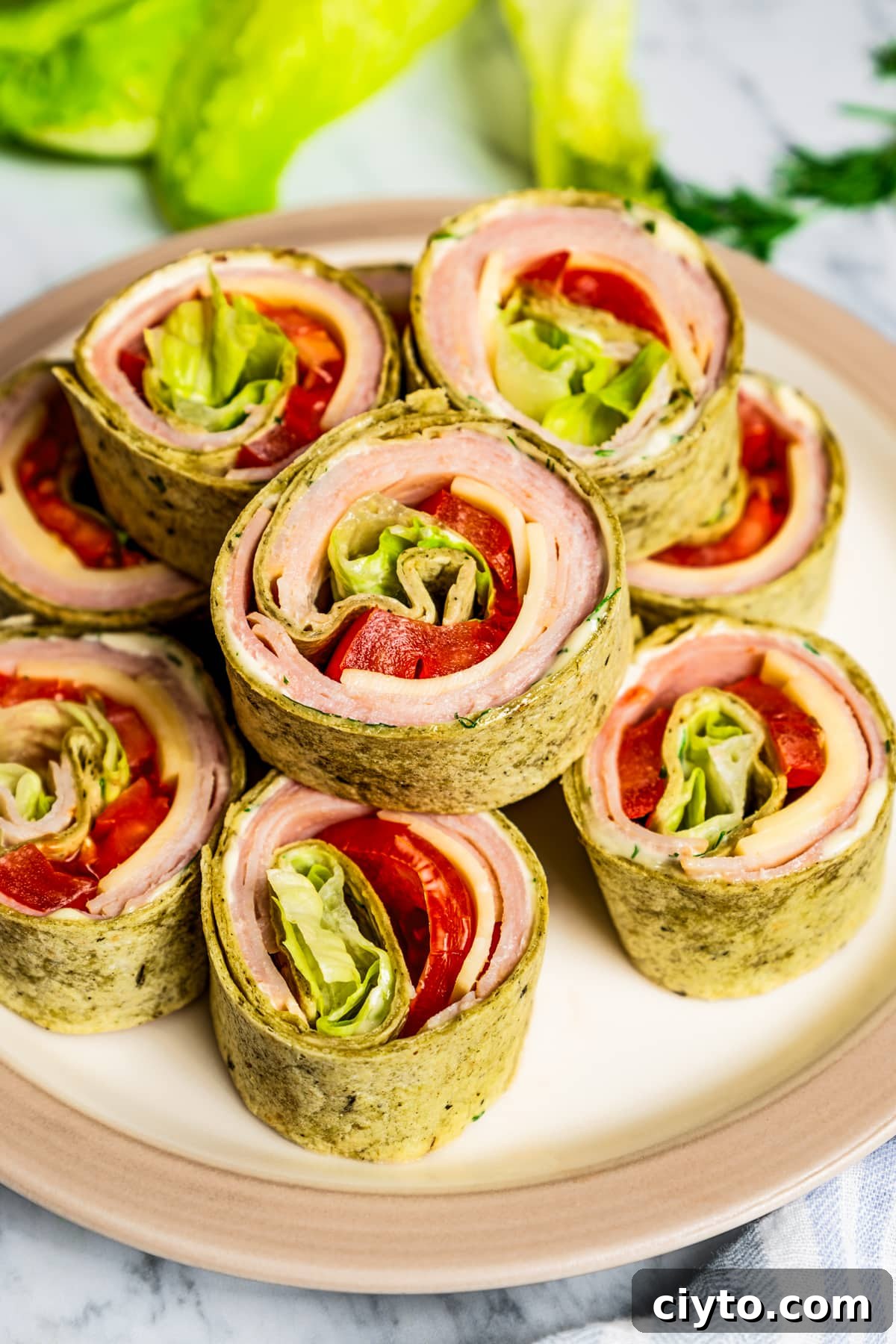 Pinwheel sandwiches stacked on a plate with a tangy Dijon mayo. Pinwheel sandwiches stacked on a plate.