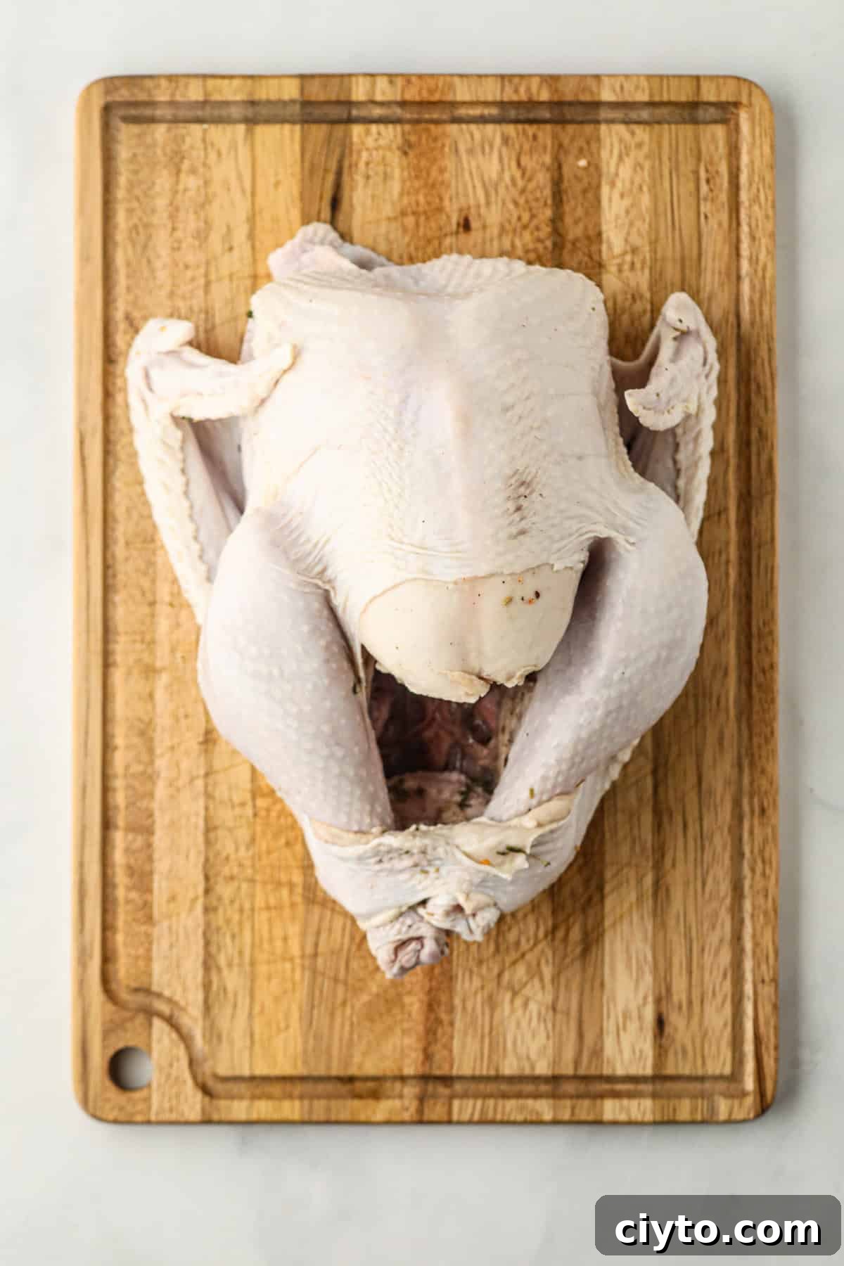 Overhead picture of partially cooked turkey on wooden cutting board.