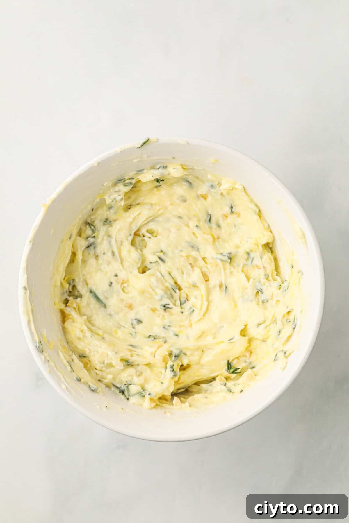 Overhead picture of white bowl with creamed butter and seasonings in it