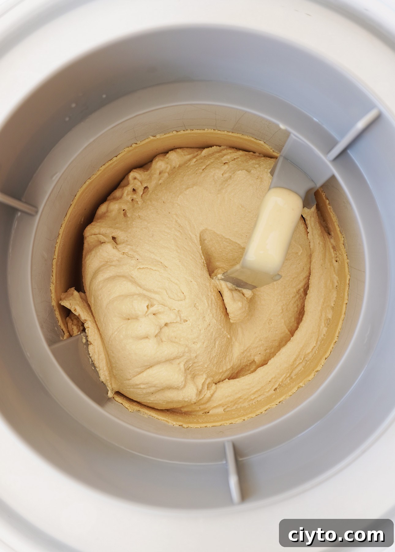 Creamy gelato being churned in an ice cream maker, the paddles swirling the mixture to a smooth, thick consistency.