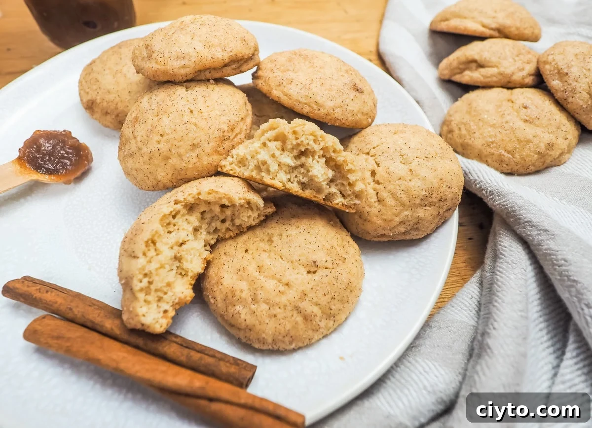 Soft Chewy Apple Butter Snickerdoodles Recipe 5 A plate of snickerdoodles with two cinnamon sticks and one broken in half on the top of the pile.