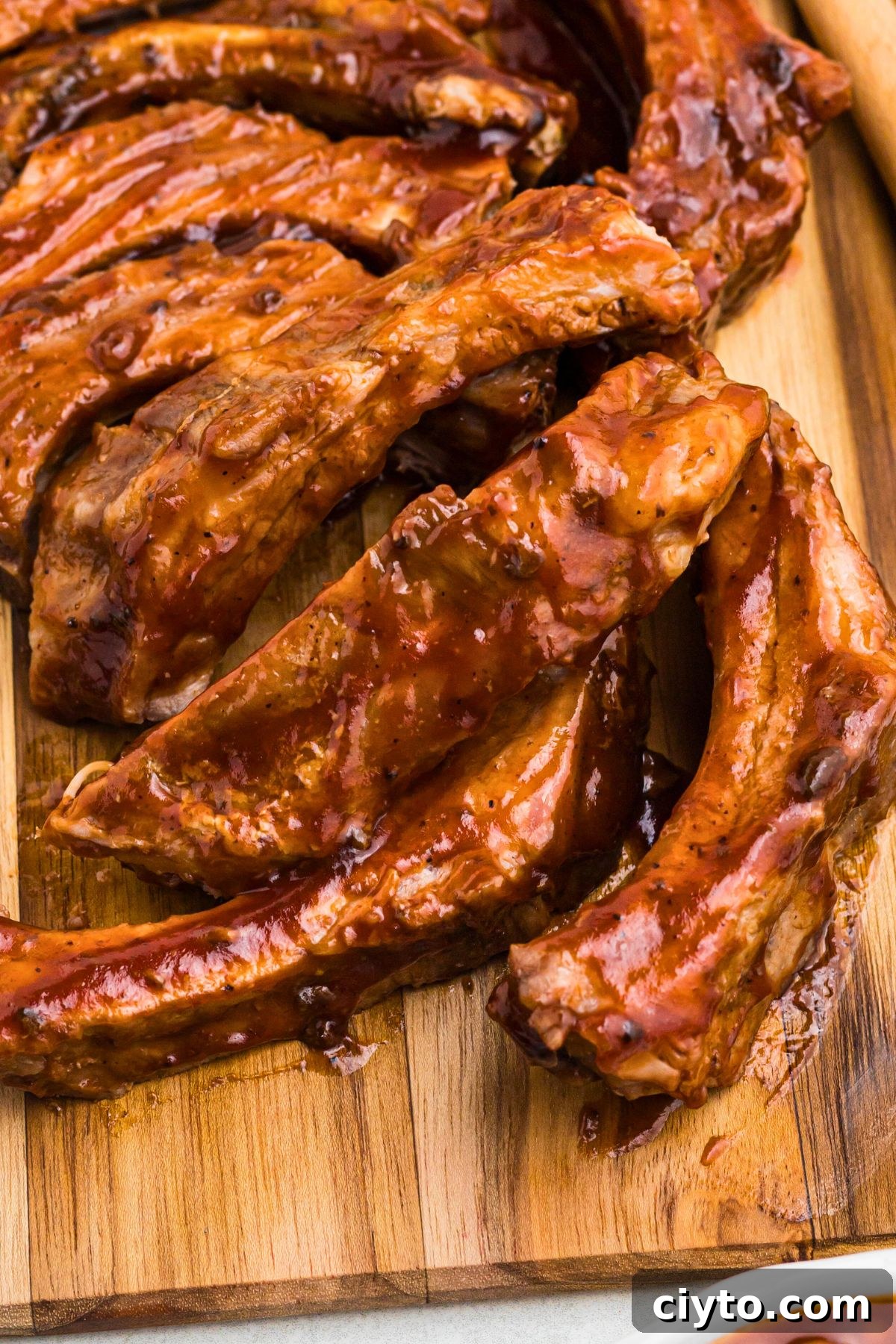 Juicy baby back BBQ ribs on a wooden cutting board.
