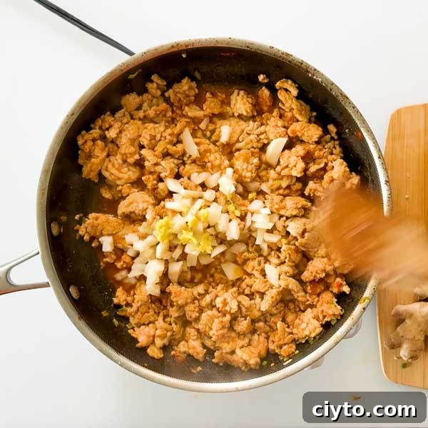 Adding the water chestnuts and ginger to the cooked meat.
