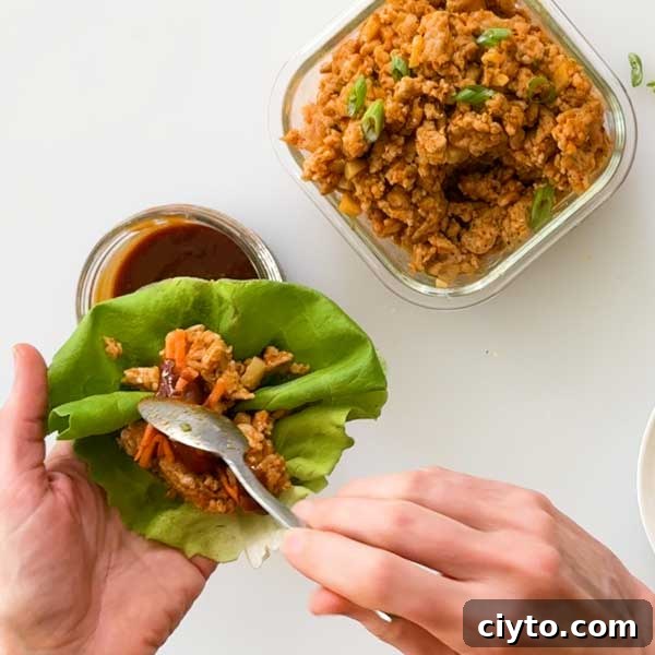 Adding the ground chicken filling to the lettuce leaf.