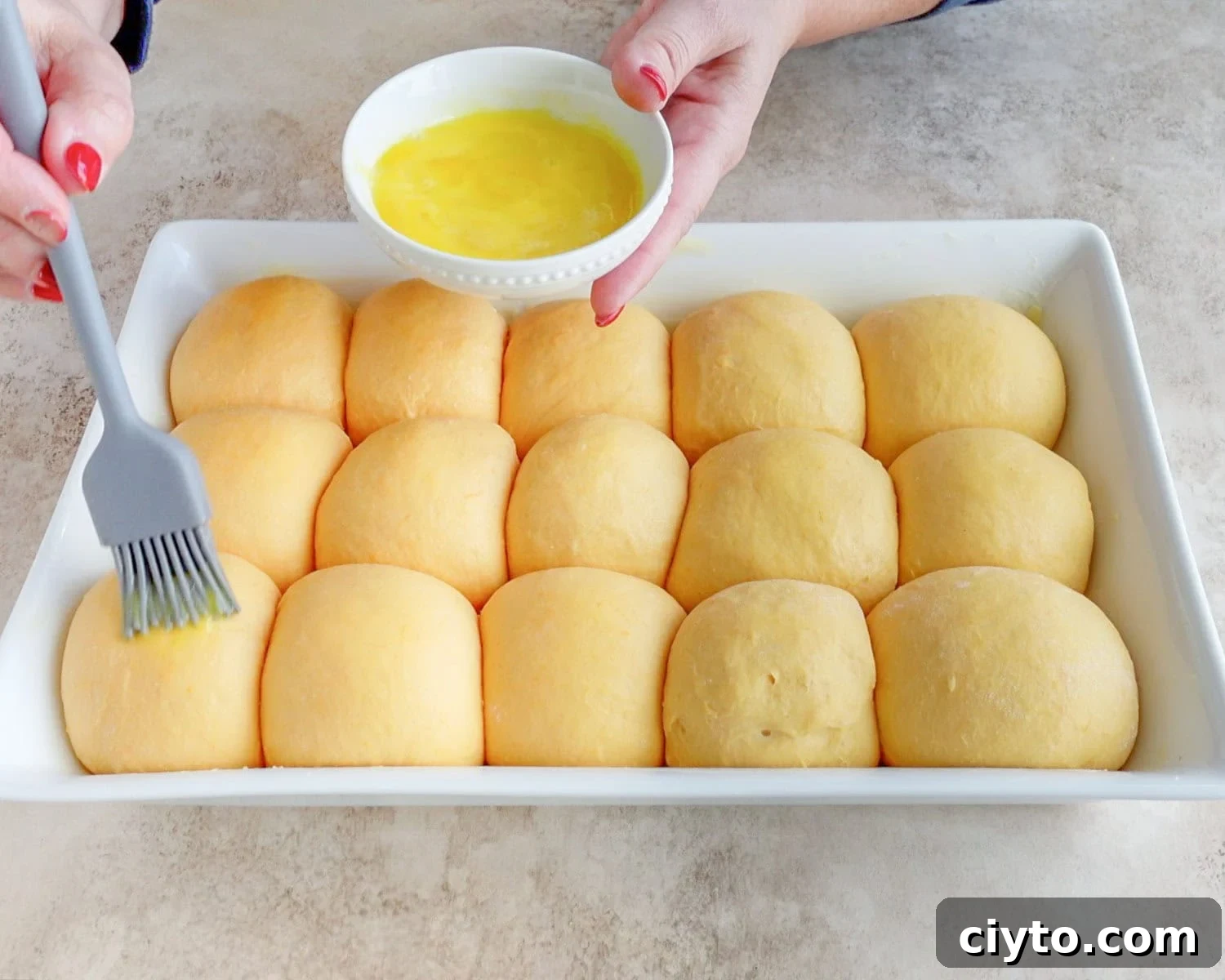 Gently brush egg wash onto dough balls.
