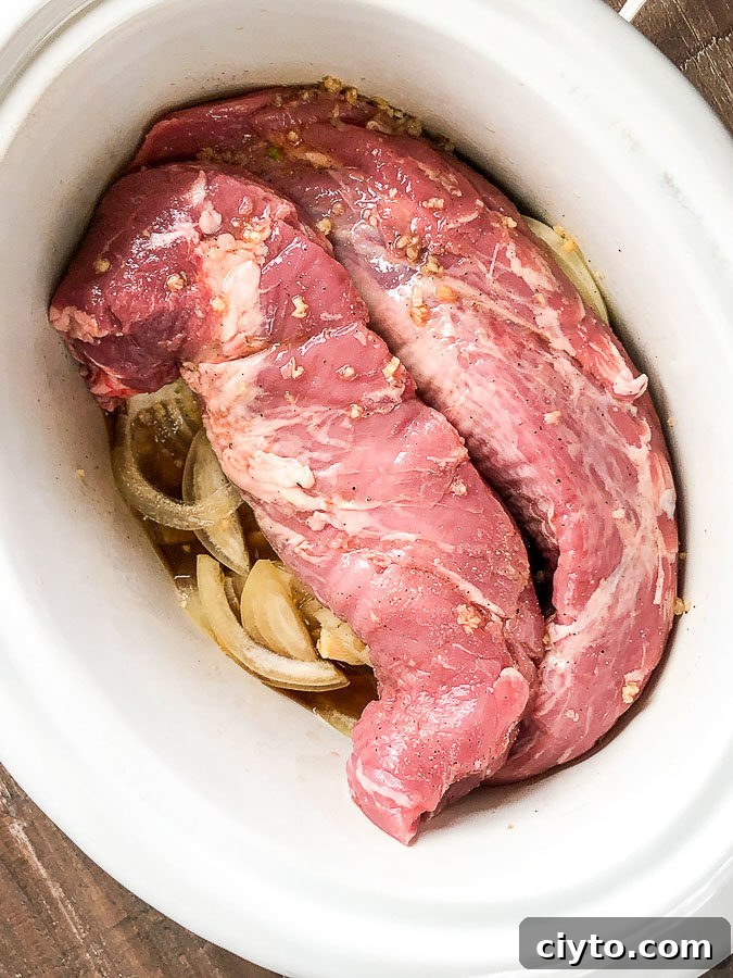 slow cooker of food, with raw pork and veggies
