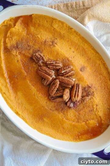 whipped sweet potatoes in casserole dish topped with pumpkin pie spice, pecans and a little maple syrup