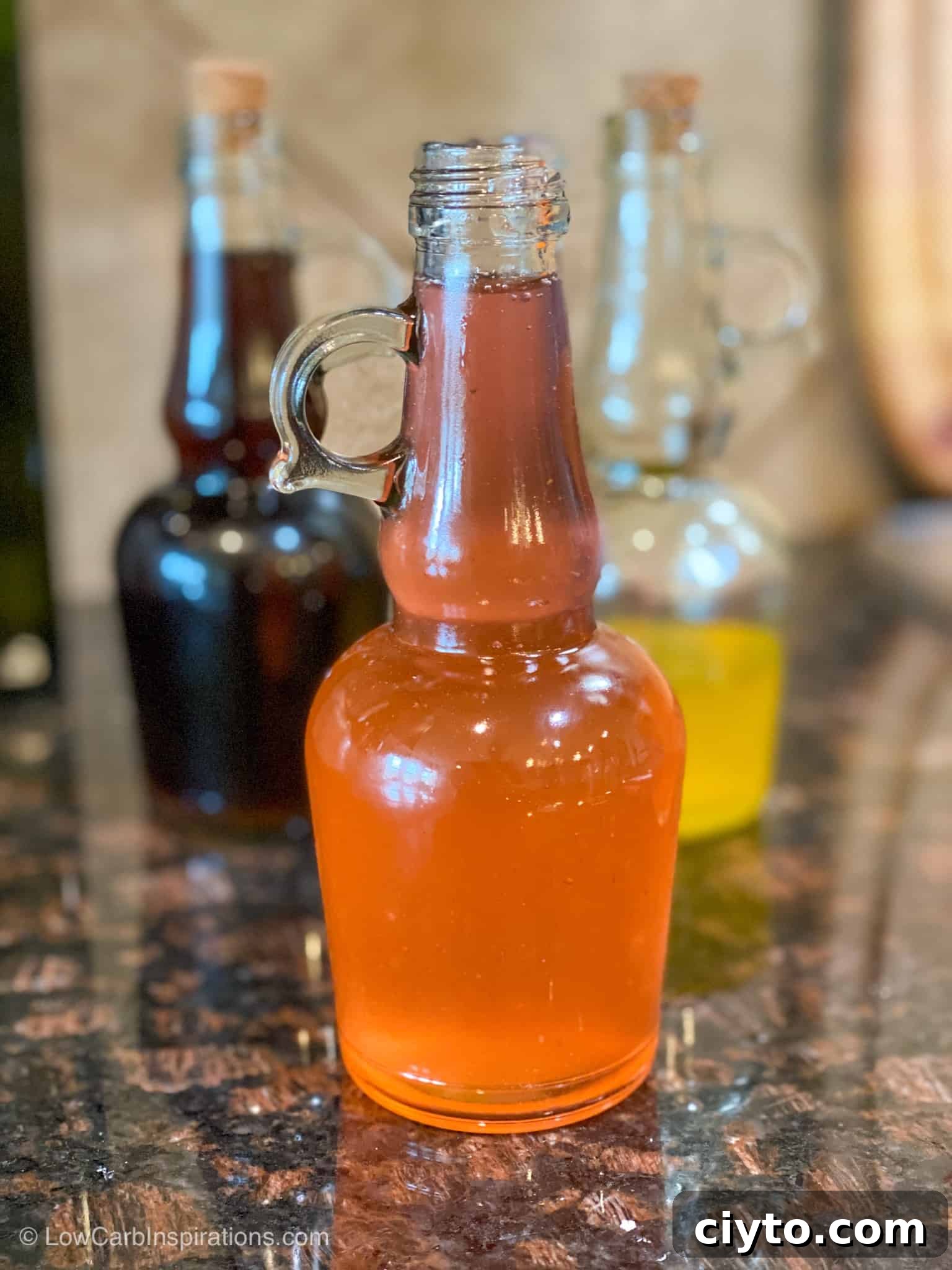 Homemade Sugar-Free Strawberry Syrup Recipe 2 Red strawberry syrup in a glass bottle sitting on the counter.
