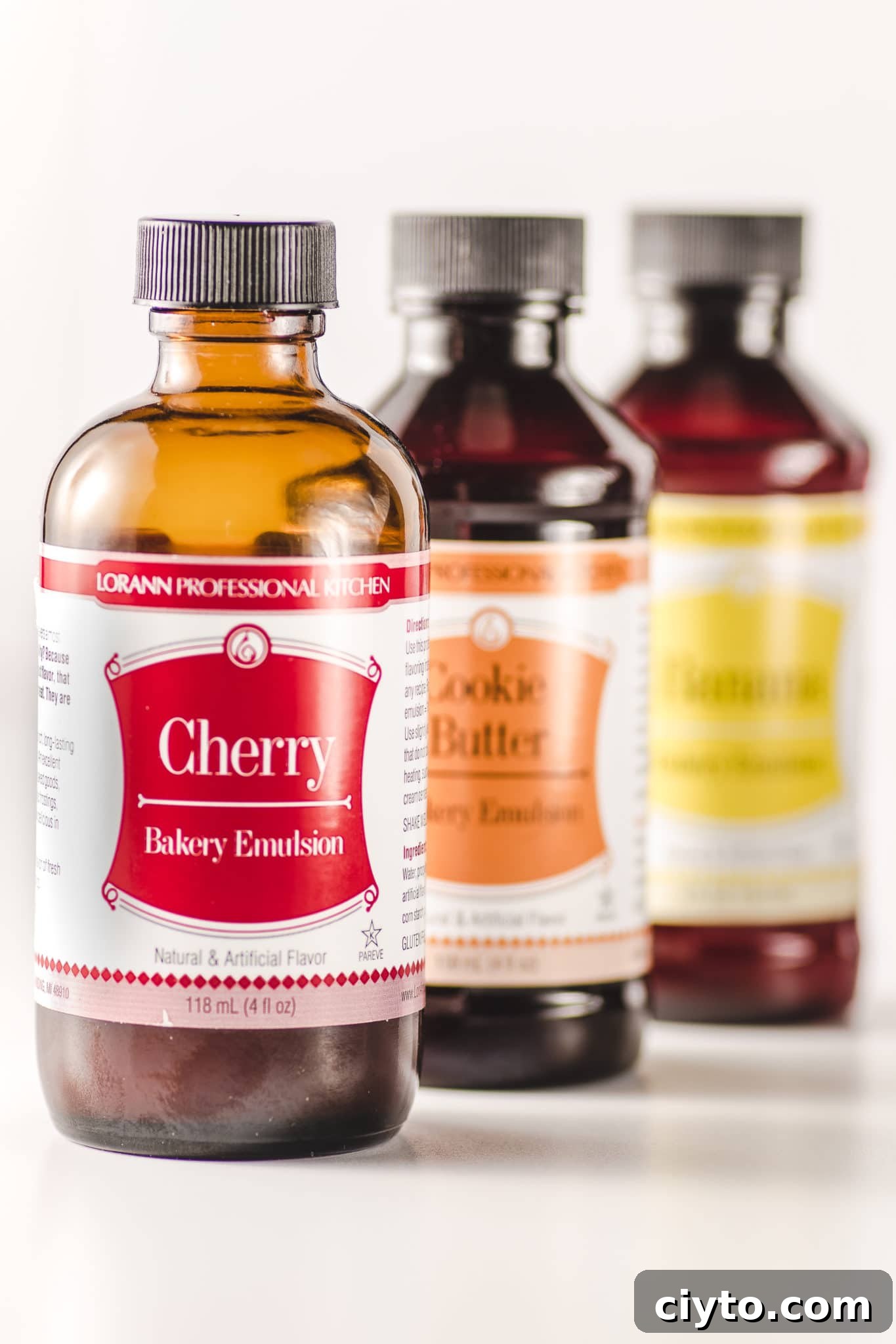 Brown glass bottles of flavored bakery emulssions with brightly colored labels on a white background