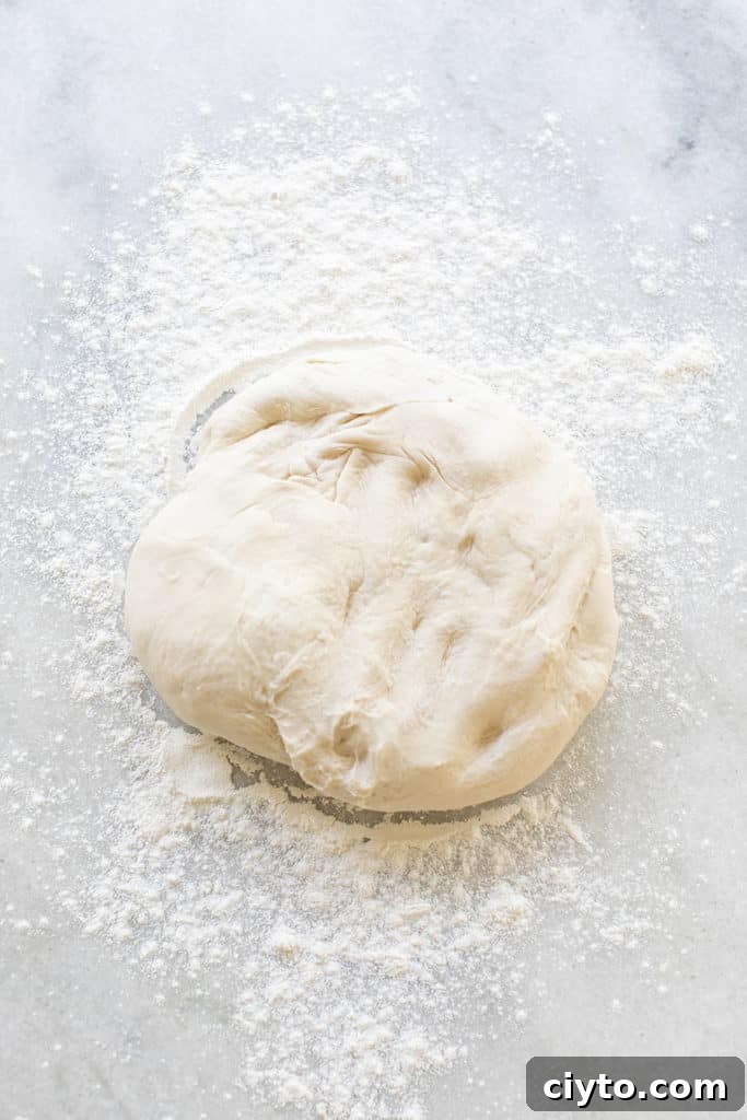 Ball of dough with flour getting ready to be rolled out for cinnamon rolls.