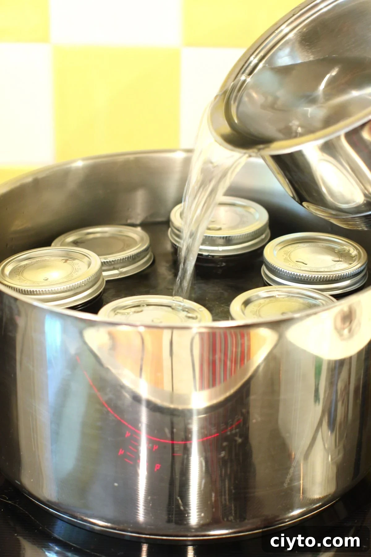 pouring water into the canner full of haskap jam jars, ready to process