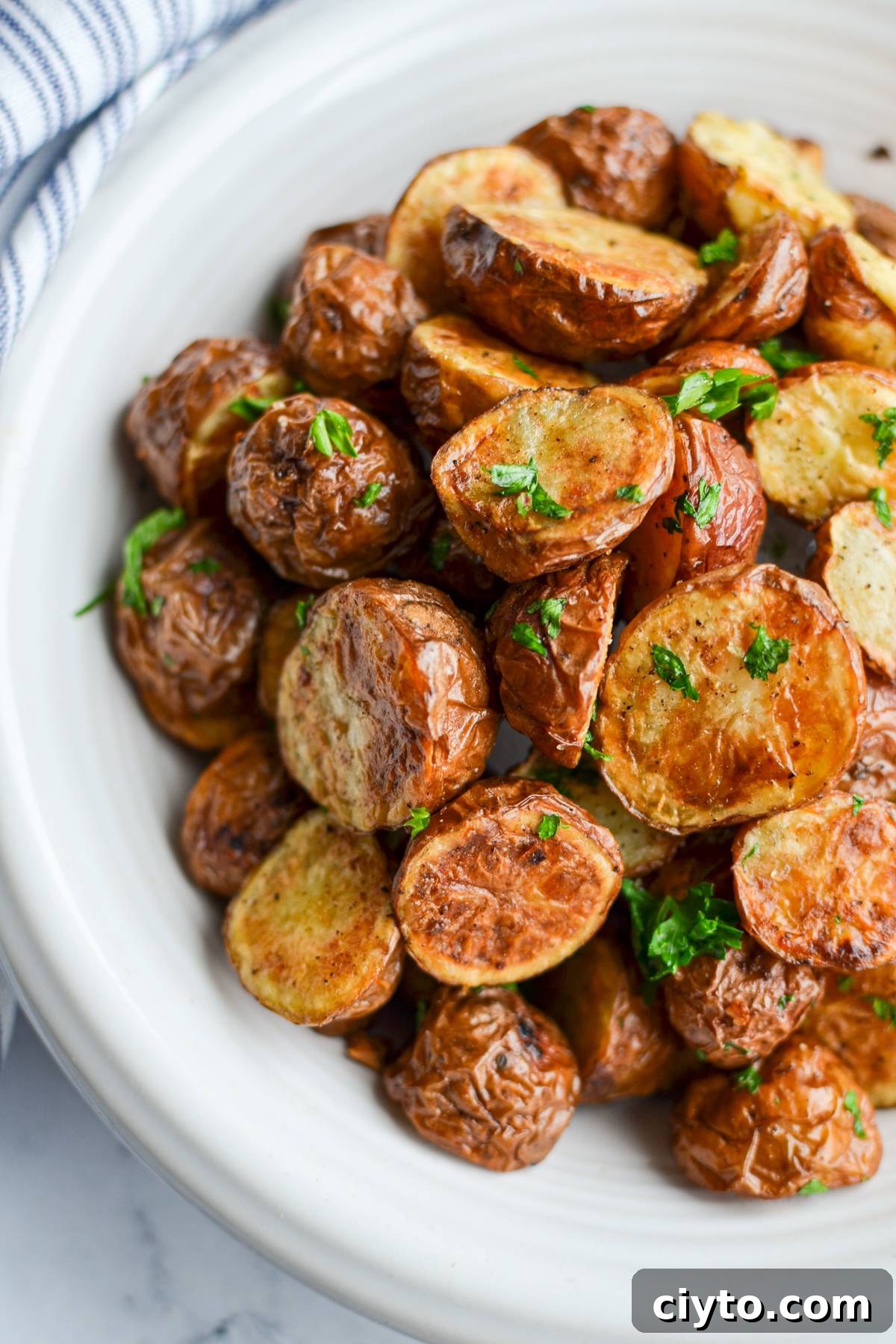 An overhead view of baby potatoes in a bowl, cooked with parsley.