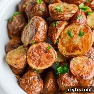 A bowl of halved and roasted baby potatoes garnished with parsley.