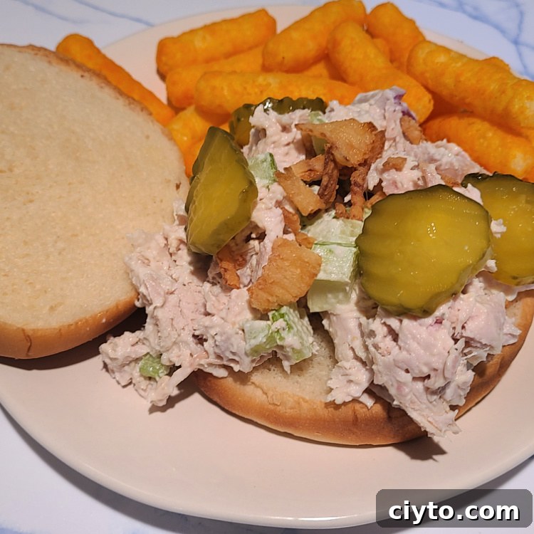 Smoked Turkey Salad on a bun on a plate served with cheese puffs