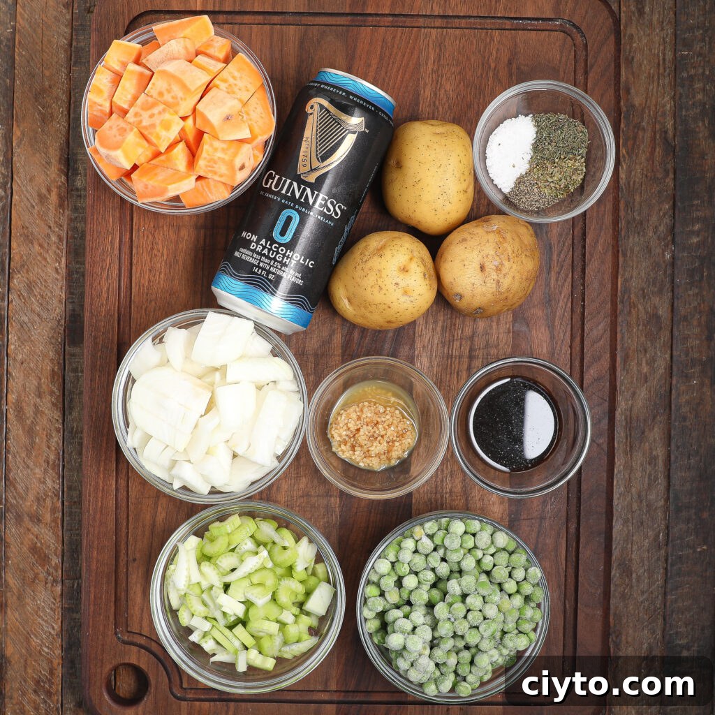 Overhead view of a wooden cutting board with bowls of diced sweet potatoes, onions, celery, frozen peas, minced garlic, and seasonings—ingredients perfect for a hearty beef Guinness pot pie—plus potatoes, Guinness 0 beer, and a small dish of dark liquid.