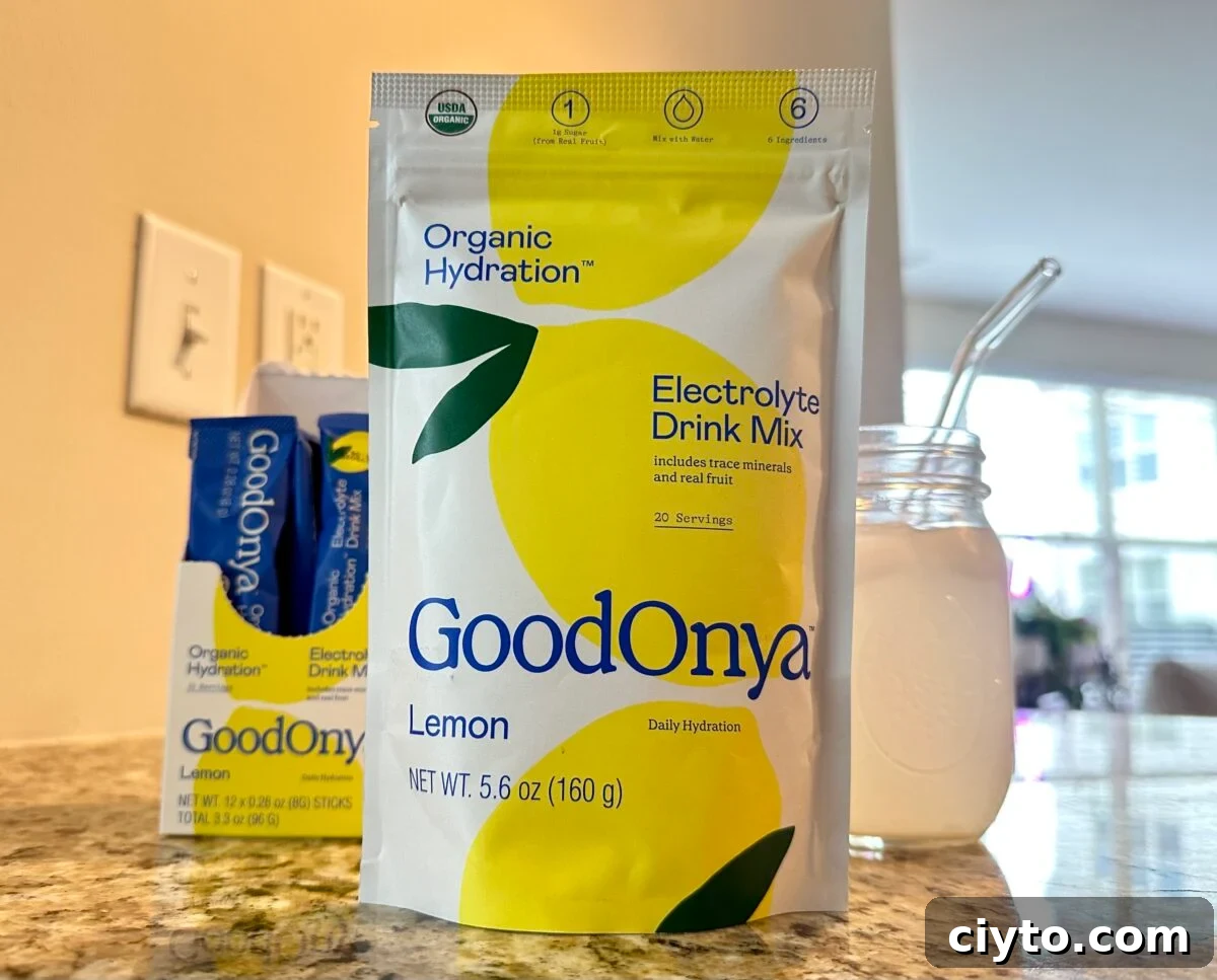The photo features a large yellow and white pouch of Goodonya Organic Hydration Lemon Electrolyte Drink Mix next to a glass of the prepared drink, with a small box of individual packets visible in the background.