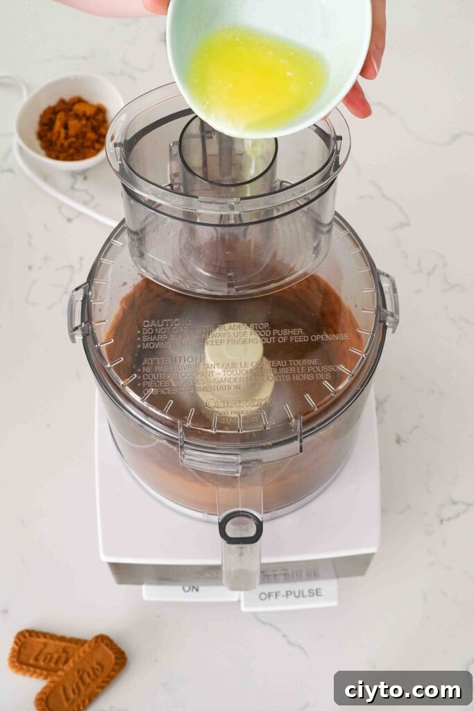 Mini Biscoff Cheesecakes Recipe with Cookie Butter Crust 5 Melted butter is poured into a food processor bowl with Biscoff cookies.