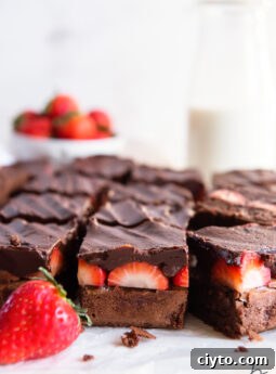 side of cut chocolate covered brownies showing layers of brownie, strawberries and chocolate ganache