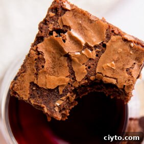 red wine brownie with a bite sitting on top of glass of red wine