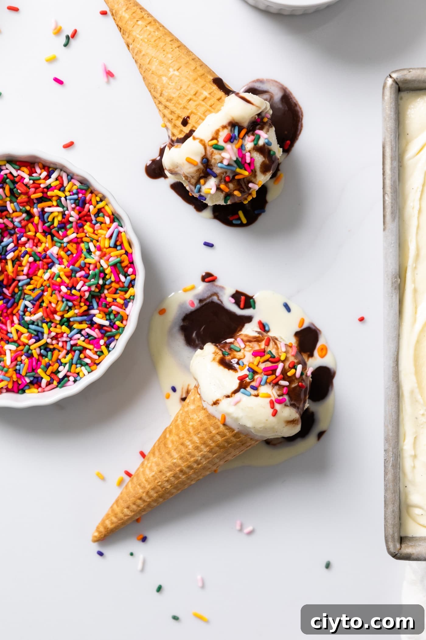 Creamy Vanilla Ice Cream Recipe with Real Vanilla Beans 4 Top down view of vanilla ice cream sitting in ice cream cones with fudge and sprinkles all over the top