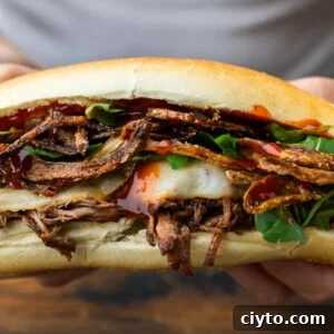 Melt-in-Your-Mouth Chuck Roast Sandwich with Crispy Onions 5 Hands holding chuck roast sandwich with crispy onions.