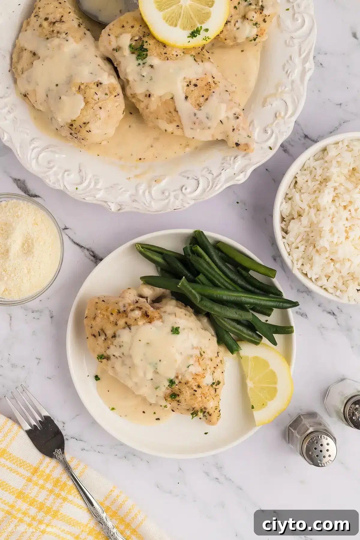 A dinner table with white plates of creamy chicken and green beans.